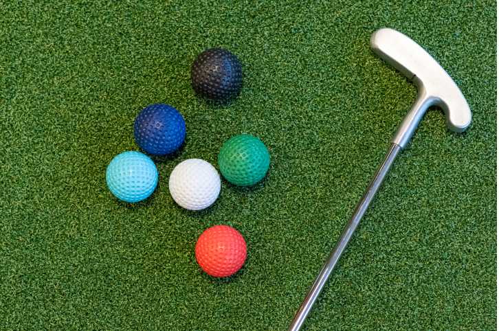 Fargerike golfballer og golfkølle på grønt gress